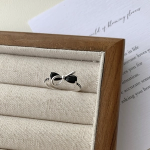 Macro shot of silver bow ring with black zircon stones on a wooden display stand