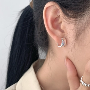 Detail of sterling silver hoop earrings with multicolored zircons on a model