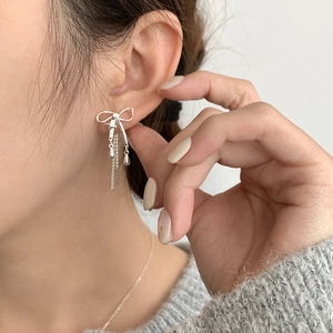 Boucles d'oreilles nœud en argent S925 avec pampilles étoile sur modèle féminin