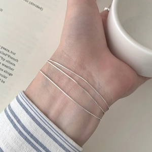 Close-up of minimalist S925 silver triple-layered snake chain bracelet on a model's wrist