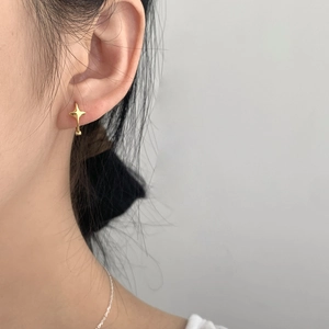 Close-up of a minimalist gold star-shaped stud earring worn on a model's earlobe