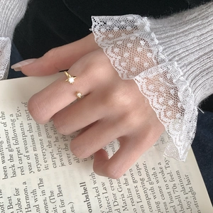 Vue détaillée d'une bague étoile dorée ajustable avec zircons portée sur un livre