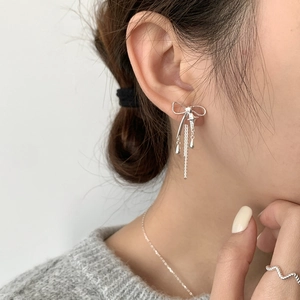 Détail de boucles d'oreilles nœud en argent S925 avec chaînes à pampilles portées par mannequin