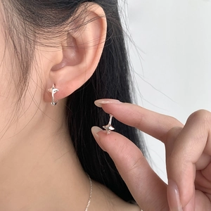 Close-up of S925 sterling silver star hoop earrings on ear and held by fingers
