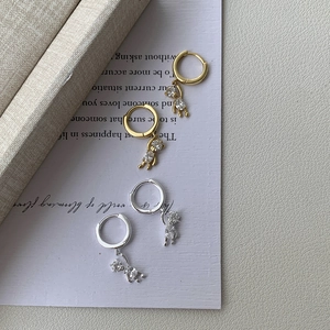 Macro detail of bear charms with micro-paved zircons on gold and silver hoop earrings