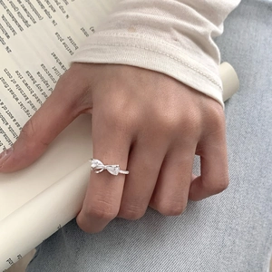 Silver bow ring with zircon stones shown on hand with a casual lifestyle backdrop