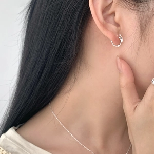 Minimalist S925 sterling silver hoop earrings with a delicate bow charm on a model
