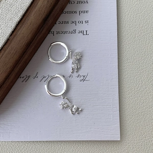Macro shot of silver bear hoop earrings with sparkling cubic zirconia on art paper