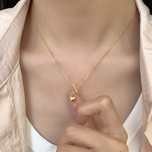 Close-up of a gold heart pendant necklace featuring a minimalist OT toggle clasp design