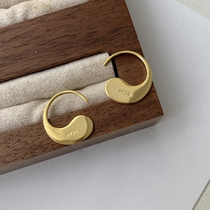 Close-up of S925 hallmark on minimalist gold teardrop earrings in a wooden jewelry box