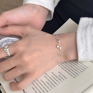 Detailed view of 925 sterling silver layered bracelet with heart and bead charms on model