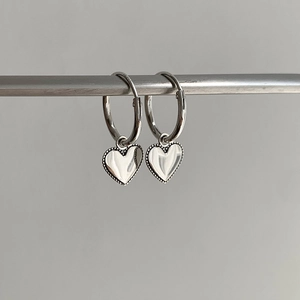 Détail de boucles d'oreilles cœur en argent S925 avec bord perlé et finition polie