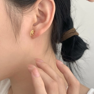 Detailed view of a minimalist golden spiral ear cuff on model with soft lighting