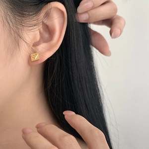 Detail of square gold heart stud earring worn on model for minimalist style