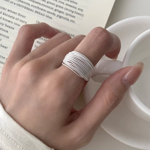 Detail of S925 sterling silver multilayer geometric ring on model hand with aesthetic decor