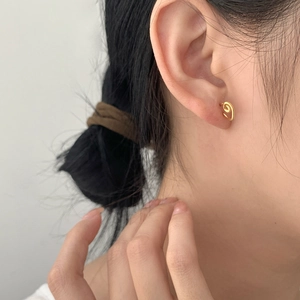 Minimalist S925 sterling silver heart-shaped gold studs worn on ear with soft lighting