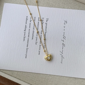 Gros plan d'un collier pendentif coeur doré avec chaîne à billes sur carte décorative