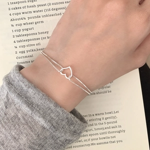 Detail of double-layer S925 sterling silver bracelet with a hollow heart pendant on wrist
