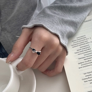 Macro shot of silver bow ring with black stones worn while holding a ceramic cup