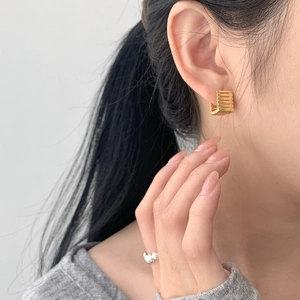 Detailed view of gold geometric hoop earrings with textured finish worn by a model