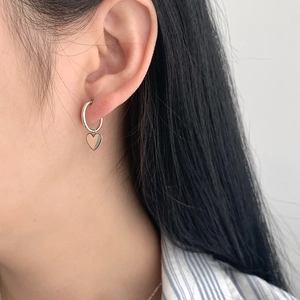 Gros plan détaillé de boucles d'oreilles cœur en argent S925 portées par un mannequin