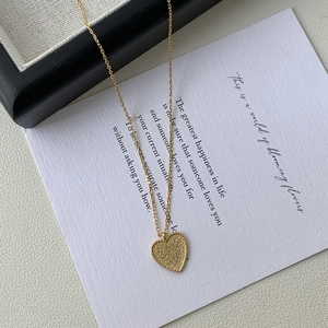 Close-up of golden heart pendant featuring frosted texture and beaded edge detail