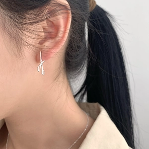 Close-up of S925 sterling silver scissor shaped hoop earrings worn by a model