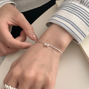 Close-up of minimalist double-layer silver bracelet with round beads worn on wrist