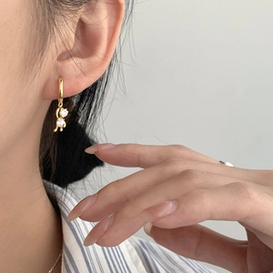 Detail view of dainty gold bear hoop earrings with sparkling crystal stones on model
