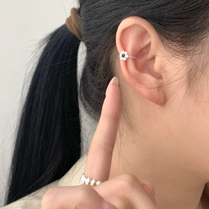 Detail of silver S925 flower ear cuff with black stone and matching wavy textured ring