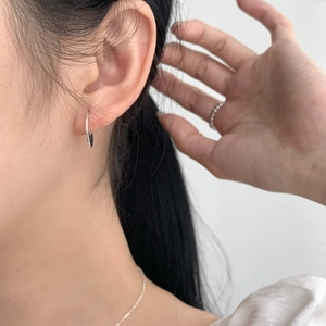Detail of minimalist S925 sterling silver curved arc earring on female model ear