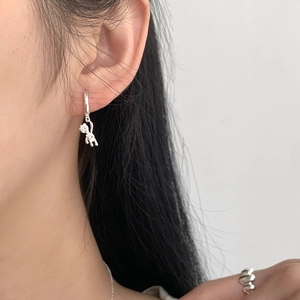 Detailed close-up of a silver bear pendant earring with sparkling zircon stones on a model