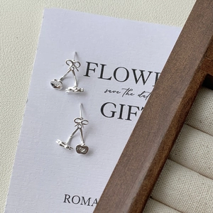 Detail shot of S925 silver bow-knot cherry stud earrings on a decorative paper card