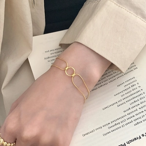 Minimalist double-layered gold bracelet with a central circle link worn on a female wrist