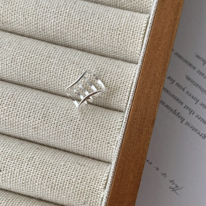 Detailed view of S925 sterling silver four-layer geometric ear cuff on beige corduroy display