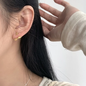 Macro view of gold bow and rabbit ear studs on earlobe, showcasing fine details