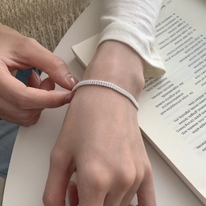 Close-up of minimalist silver double-row pave zircon bracelet worn on woman wrist