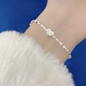 Detail of 925 sterling silver beaded bracelet with heart charm on female wrist