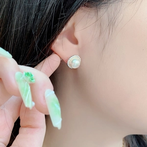 Close-up of S925 sterling silver pearl stud earrings with twisted border on ear