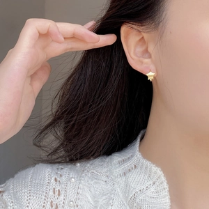 Close-up of matte gold star stud earrings worn by a model for an elegant daily look