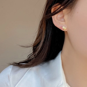 Close-up of a minimalist golden knot earring worn by a model for a refined look