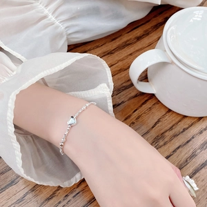 Detail of 925 sterling silver beaded bracelet with heart charm on a model wrist