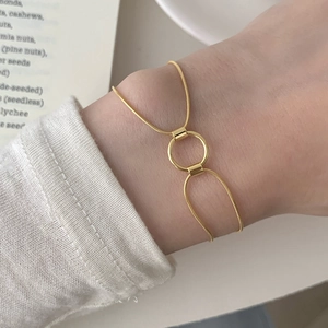 Close-up of a double-layered golden snake chain bracelet with interlocking circles on a wrist