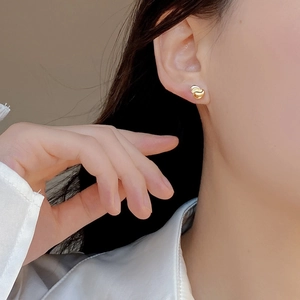 On-ear display of minimalist 925 silver knot earrings in a polished golden finish