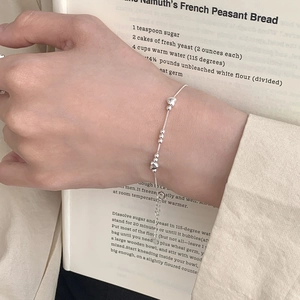 Detail of S925 sterling silver heart and bead bracelet worn on a model wrist over a book