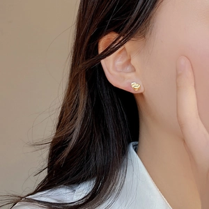 Minimalist 925 sterling silver two-tone knot stud earrings worn on a model ear