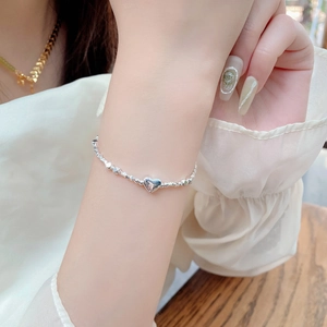 Close-up of 925 sterling silver heart charm bracelet with faceted silver beads on wrist