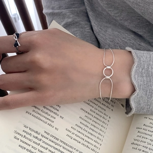 Close-up of S925 silver interlocking circle bracelet and black bow ring on model