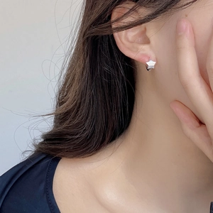Close-up of minimalist S925 sterling silver star stud earrings worn on ear