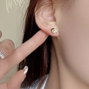Detail of minimalist 925 silver heart stud earrings with two-tone gold and silver finish